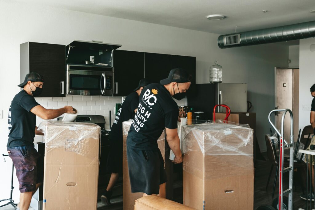 Team of movers unpacking boxes in a modern kitchen setting. Efficient and organized moving service.