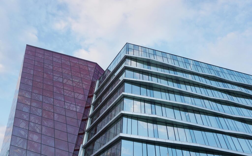 Contemporary urban architecture with glass and red facade against blue sky.