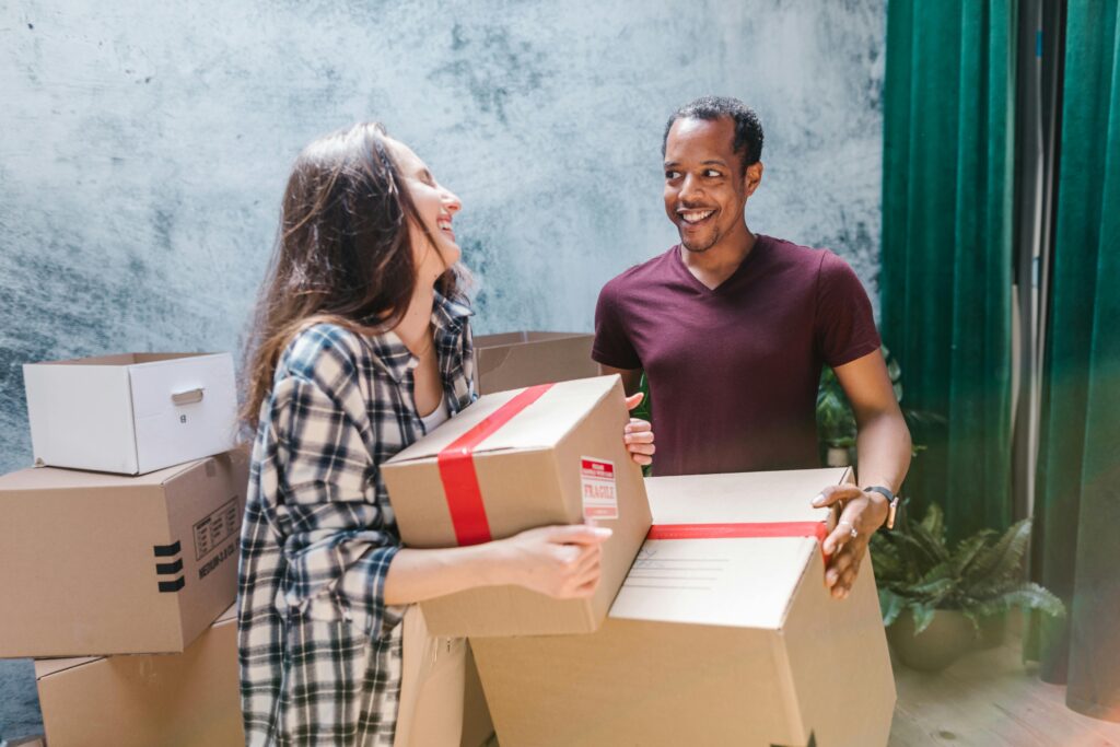 Happy couple moving boxes into their new home, creating fresh memories together.